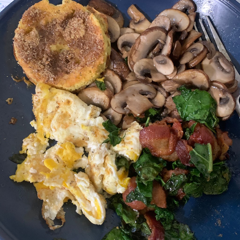 Keto breakfast food eggs, mushrooms, bacon, kale and biscuit