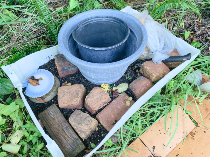 Compost bin covered with bricks and pots for worms