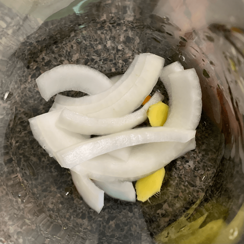 Onion slices, ginger and Aji hot peppers in the bottom of a jar.