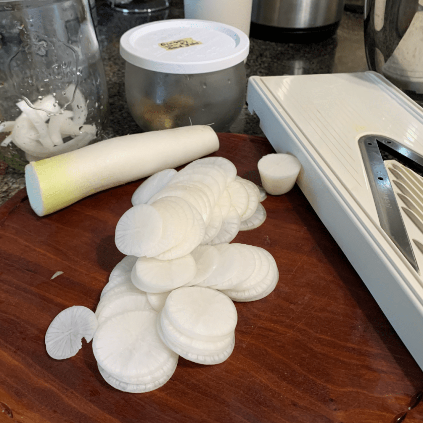 Slicing the daikon radish using a mandolin slicer.
