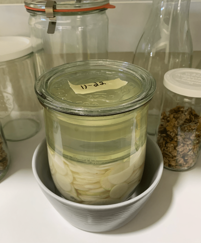 Daikon radish sliced in a jar and fermenting in brine.